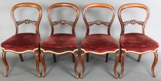 A set of 4 Victorian mahogany balloon back dining chairs with carved shaped mid rails, the seats of serpentine outline raised on French cabriole supports 