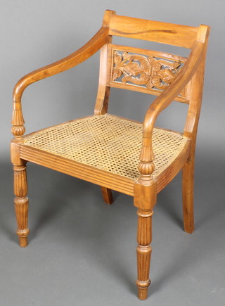A Regency style mahogany bar back carver chair with pierced mid rail and woven cane seat, raised on turned and reeded supports 