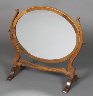 An oval plate dressing table mirror contained in a mahogany swing frame with satinwood stringing 17"h x 19"w 