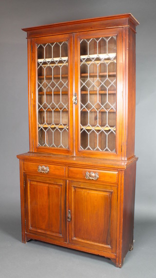 An Edwardian Art Nouveau walnut bookcase on cabinet, the upper section with moulded cornice, fitted adjustable shelves enclosed by lead glazed panelled doors, the base fitted 2 drawers above a double cupboard 80"h x 41"w x 16"d 