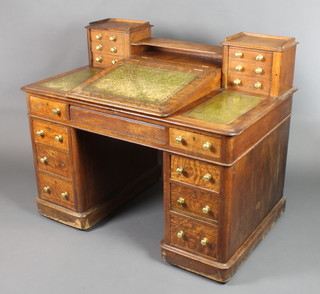 A Victorian oak Dickens style desk, the raised super structure fitted a recess flanked by 6 short drawers, the writing surface fitted a slope above 1 long and 8 short drawers