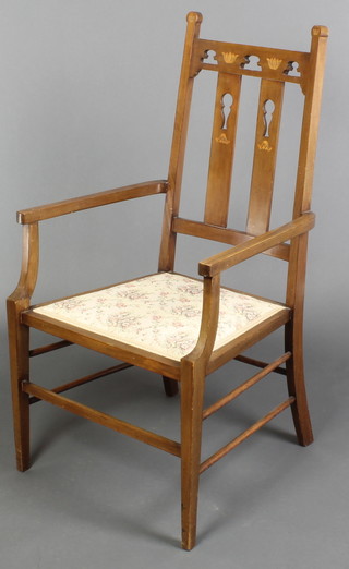 A Liberty's style inlaid mahogany open arm stick and rail back chair with upholstered seat raised on square tapering supports 