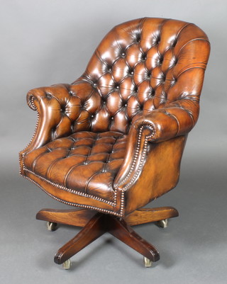 A tub back revolving office chair upholstered in brown buttoned hide 