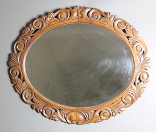 A Victorian oval bevelled plate wall mirror contained in a carved and pierced oak frame, carved "The Green Man" 28" x 33" 