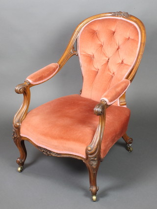 A Victorian carved walnut show frame open arm chair upholstered in pink buttoned Dralon, raised on cabriole supports 