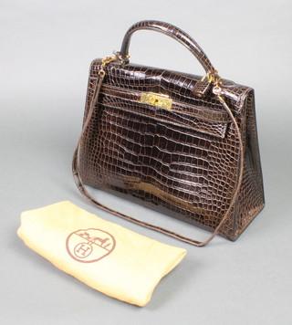 Hermes, a lady's brown crocodile "Kelly" handbag, stamped to the inside Hermes Paris. Made in France, with lock, key and shoulder strap, together with a Hermes dust bag, 8 1/4" high x 11 1/4" wide 