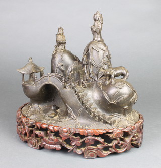 An unusual late 18th Century Chinese bronze of an island with steps up to a pagoda with 3 mountain tops, 2, each with a figure and 1 with a buffalo, the mountain with peony and bamboo above a carp amongst the waves, on a hardwood stand 11" x 9 1/2" 