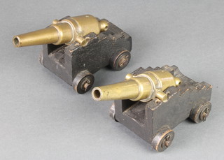 A pair of 19th Century brass table top cannons with 6" drilled barrels, raised on wooden trunnions 