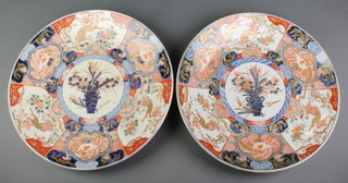 A pair of 19th Century Imari dishes decorated with panels of stylised lions, birds and flowers enclosing a central medallion of a vase of flowers 14" 