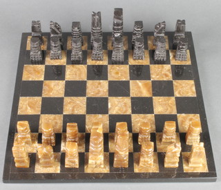 An Aztec style carved marble chess set and board 