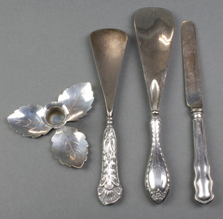 A silver handled butter knife, 2 shoe horns and a candle holder 