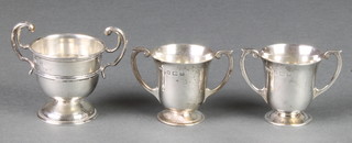 An Edwardian silver miniature 2 handled trophy 2" Sheffield 1903, a pair of similar miniature trophy cups 2" Birmingham 1912, 92 grams 