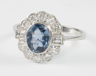 An 18ct white gold oval sapphire and diamond cluster ring the centre stone 1.65ct surrounded by 10 brilliant cut diamonds and 2 baguette cut ditto approx. 0.75ct, size P 