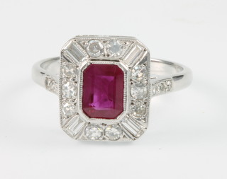 An 18ct white gold Art Deco style ruby and diamond ring, the centre baguette cut stone flanked by 10 brilliant cut diamonds and 4 baguette cut diamonds, size L 1/2