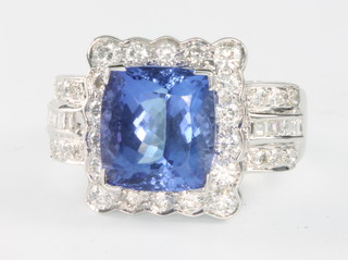 A 14ct white gold tanzanite and diamond ring the cushion cut centre stone 6.75ct surrounded by princess and brilliant cut diamonds 1.3ct size R 1/2