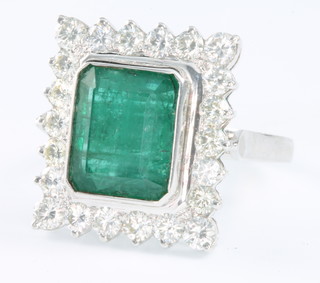 A 14ct white gold emerald and diamond ring the rectangular cut centre stone 6.6ct surrounded by 22 brilliant cut diamonds 2.1ct size R