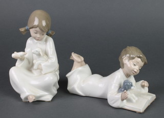 A Nao figure of a reclining boy reading a book 1285 8" and ditto figure of a seated girl feeding a lamb 1275 7" 