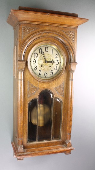 An Edwardian chiming wall clock with 8" brass and silvered dial, Arabic numerals, contained in an oak and bevelled glass case
