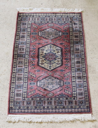A pink and white ground Persian rug with lozenge shaped diamond to the centre within multi-row borders 62" x 37" 