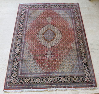 A Persian Tabriz red and green ground carpet with central medallion, in wear,  118" x 83"  