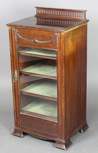 An Edwardian mahogany music cabinet having a raised back with fluted decoration, enclosed by a glazed panelled door with swag decoration to the top, raised on ogee bracket feet 38"h x 18 1/2"w x 15 1/2"d 