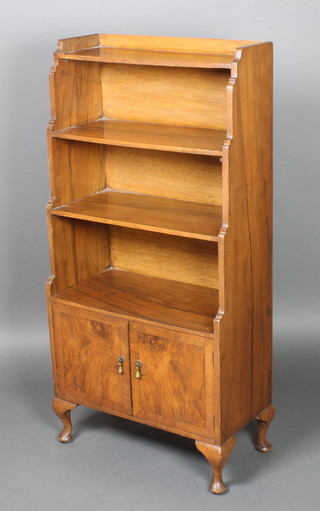 A 1930's Art Deco walnut 4 tier waterfall bookcase, the base enclosed by panelled doors, raised on cabriole supports 48"h x 23 1/2"w x 12"d 
