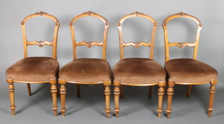 A set of 4 Victorian carved walnut balloon back dining chairs with shaped mid rails, raised on turned supports 