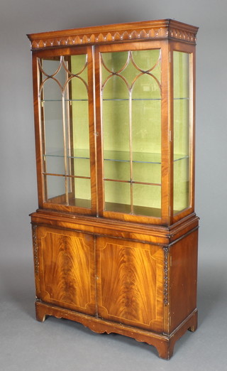 A Georgian style mahogany display cabinet on cabinet, the upper section with shaped cornice the interior fitted shelves enclosed by astragal glazed doors, the base fitted a cupboard enclosed by panelled doors 67"h x 36"w x 15"d 