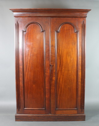 A Victorian mahogany wardrobe with moulded cornice, fitted hanging space and 6 trays enclosed by a pair of arched panelled doors 88"h x 61"w x 25 1/2"d 