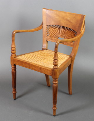 A Regency style Anglo Indian teak bar back open arm chair with pierced back and woven cane seat, raised on turned and reeded supports