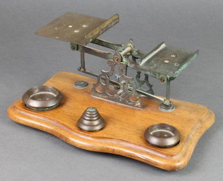 A set of brass postage scales complete with weights, raised on a shaped base
