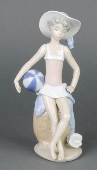 A Lladro figure of a seated girl holding a beach ball bedside a seashell 5219 boxed 8" 