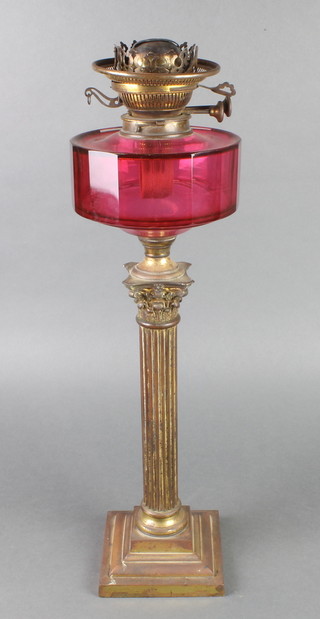 A Victorian cranberry glass oil lamp reservoir raised on a brassed Corinthian column 
