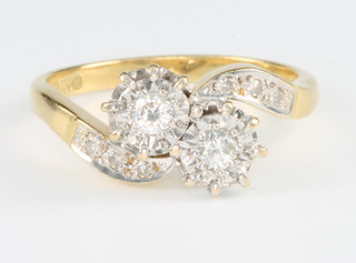 An 18ct yellow gold 2 stone diamond cross-over ring with diamond shoulders, size O 1/2