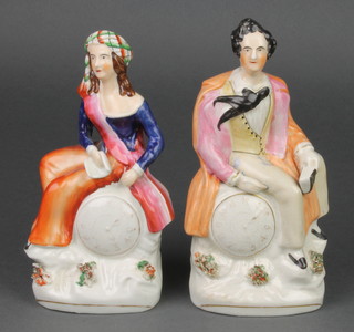 A pair of Victorian Staffordshire figures of a gentleman and lady sitting on clocks with applied floral decoration 8" 