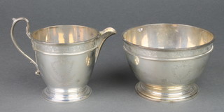 A silver cream jug and sugar bowl with floral rim and vacant shield cartouche London 1922, 398 grams