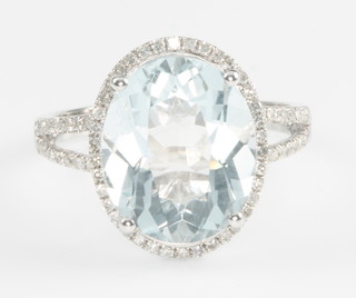 A 14ct white gold oval cut aquamarine ring, the centre stone approx. 5.5ct surrounded by diamonds approx. 0.5ct, size M 1/2