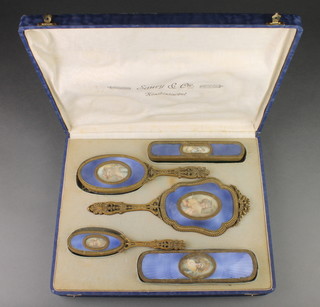 An early 20th Century gilt and guilloche enamel dressing table set with hand mirror, 2 hairbrushes, 2 clothes brushes, each with different painted miniature portraits of ladies in a fitted case