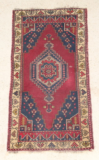 A red and blue ground Persian rug with diamond medallion to the centre, in wear 75" x 38" 