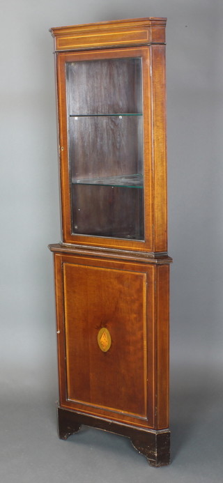 An Edwardian inlaid mahogany double corner cabinet, the upper section with moulded cornice, fitted shelves enclosed by a glazed panelled door, the base enclosed by a panelled door, raised on bracket feet 75"h x 22"w x 14"d, the base 25" x 14 1/2"