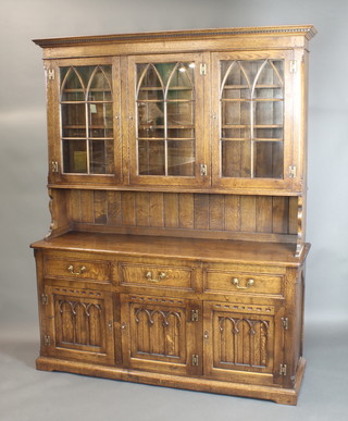 A carved oak 17th Century/18th Century style dresser, the raised back with moulded and dentil cornice, fitted 3 cupboards with adjustable shelves enclosed by arched astragal glazed panelled doors above a recess, the base fitted 3 long drawers above a triple cupboard with arcaded decoration and brass H framed hinges, raised on a platform base 83"h x 67"w x 20"d 
