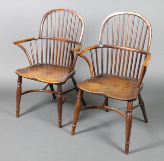 A pair of 19th Century elm and yew stick and hoop back Windsor chairs with solid seats raised on turned supports with crinoline stretchers 