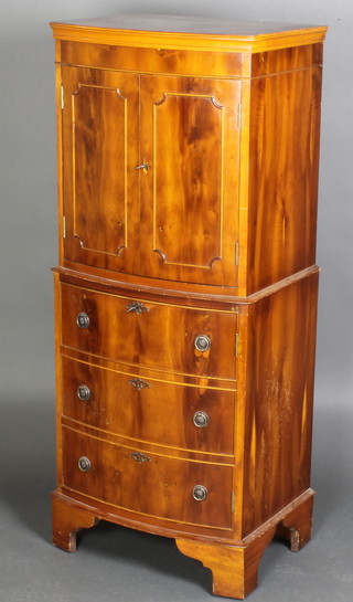 A Georgian style yew bow front cocktail cabinet, the upper section with moulded cornice fitted a cupboard enclosed by panelled doors, the base enclosed by a panelled door in the form of faux long drawers, raised on bracket feet 52"h x 21"w x 16"d 
