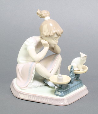 A Lladro group of a seated girl looking at a kitten on a set of scales 5474 6 1/4" 