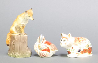 A Royal Crown Derby Japan pattern paperweight in the form of a cat Spice 3 1/2" with gold stopper, a ditto of a teal duckling with gold stopper 2 1/2" and a Nymphenburg figure of a fox sitting on a tree stump 4 3/4" 