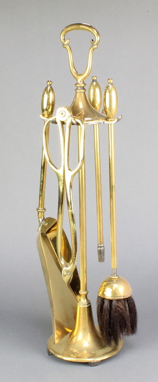 An Art Nouveau style brass 4 piece fireside companion set comprising poker, shovel, brush and tongs, compete with stand