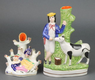A Victorian Staffordshire spill vase in the form of a couple sleeping beneath a tree, bearing a label from Lieutenant Colonel A C W Kimptons Collection no. 858 5", together with a reproduction ditto of a farmer and cow 9" 