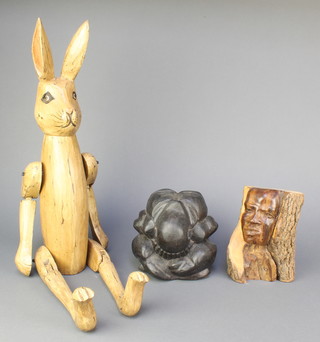 A carved hardwood figure of a hare with articulated limbs 26", a Chinese carved hardwood figure of  a kneeling man 5", an African carved portrait bust of a man formed from a tree trunk 7"