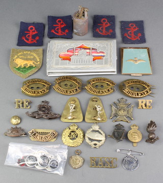 A collection of WWII and later cap badges, a trench art cigarette lighter and a POW cigarette case