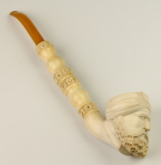 A carved Meerschaum pipe with floral decorated stem, the bowl in the form of a man's head with an amberoid mouthpiece 11" 